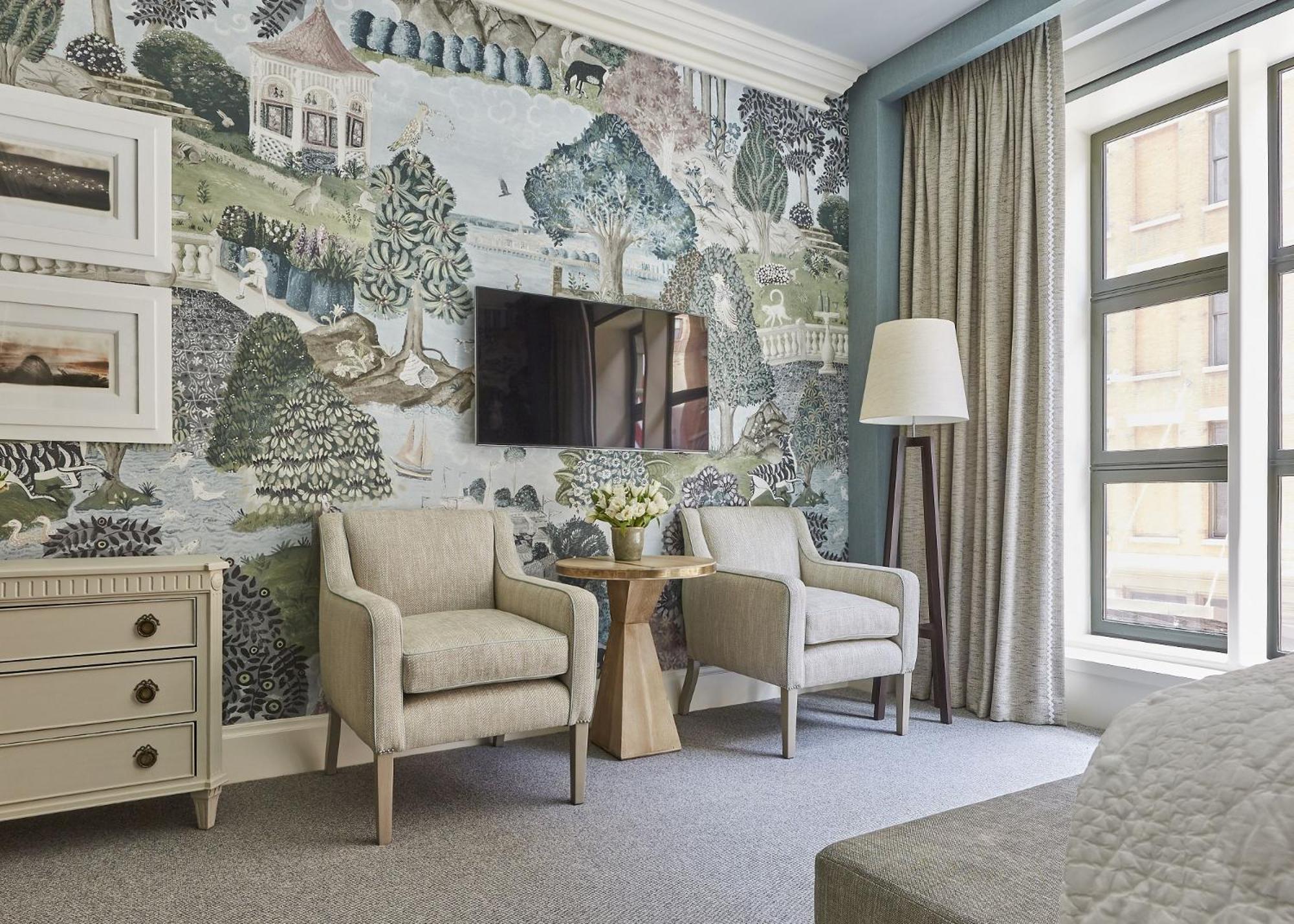 Whimsical botanical wallpaper transforms this corner into a verdant retreat, where neutral armchairs invite lingering over morning coffee beside oversized windows.