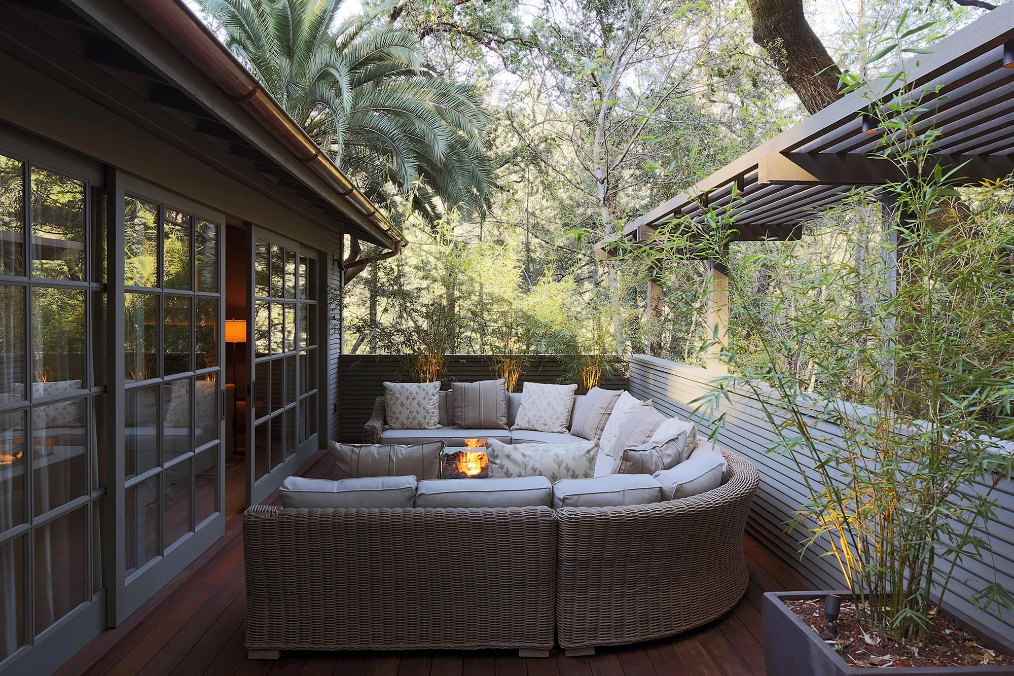 Wicker sectionals curve around a crackling fire pit on this private deck, where towering oaks and bamboo create an intimate forest sanctuary.