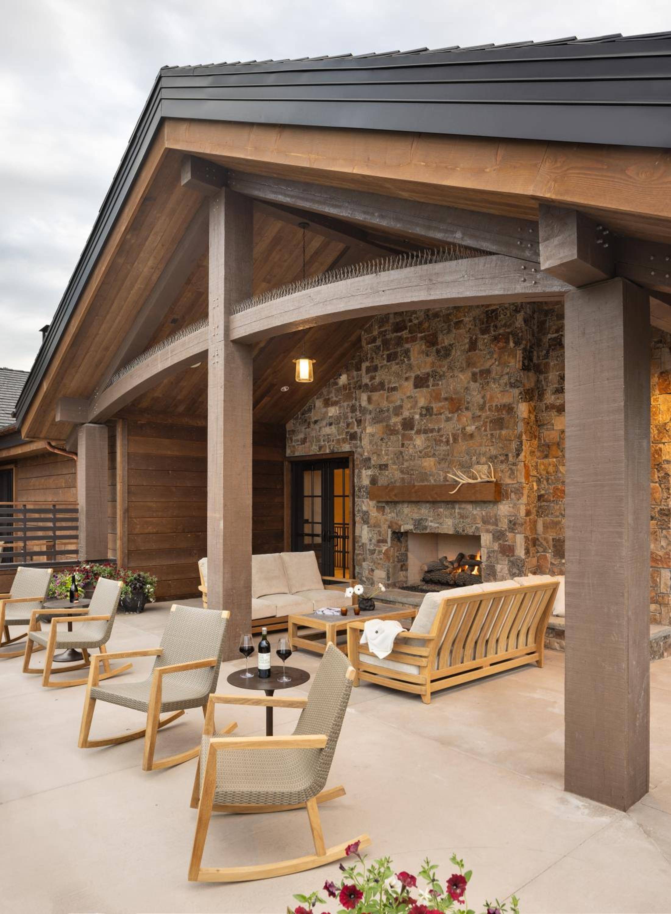 Stone and timber converge under soaring beams, where crackling fires and handcrafted teak seating create an alpine sanctuary for evening wine and mountain contemplation.