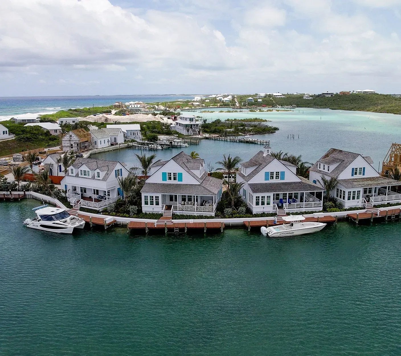 Weathered-shingle cottages with turquoise shutters line a wooden dock where sailboats bob in crystalline waters, epitomizing Abaco's laid-back island charm.