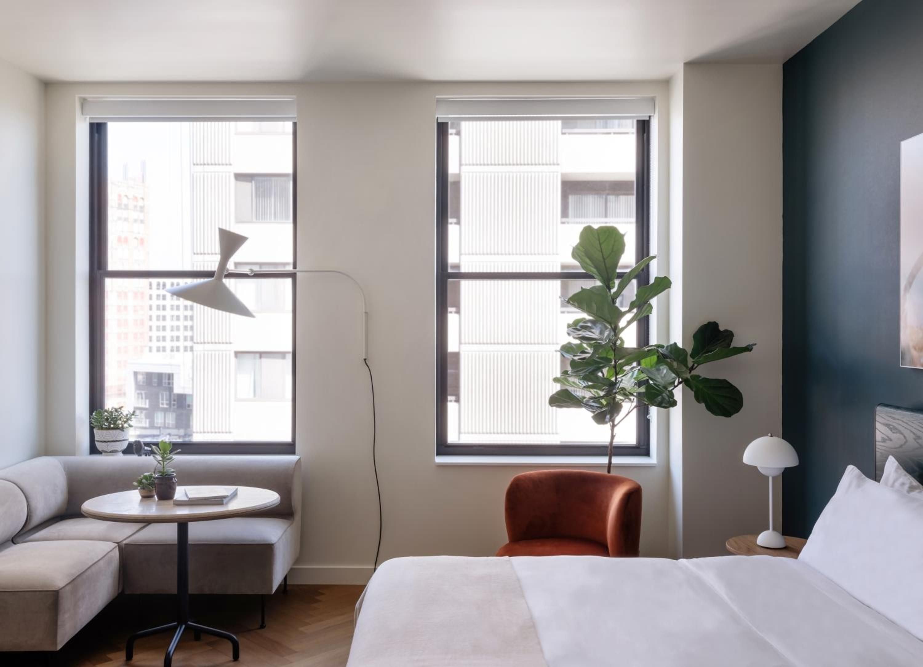 Floor-to-ceiling windows frame Detroit's urban landscape while burnt orange velvet chairs and sculptural floor lamps create intimate corners for unwinding in these thoughtfully designed guest rooms.