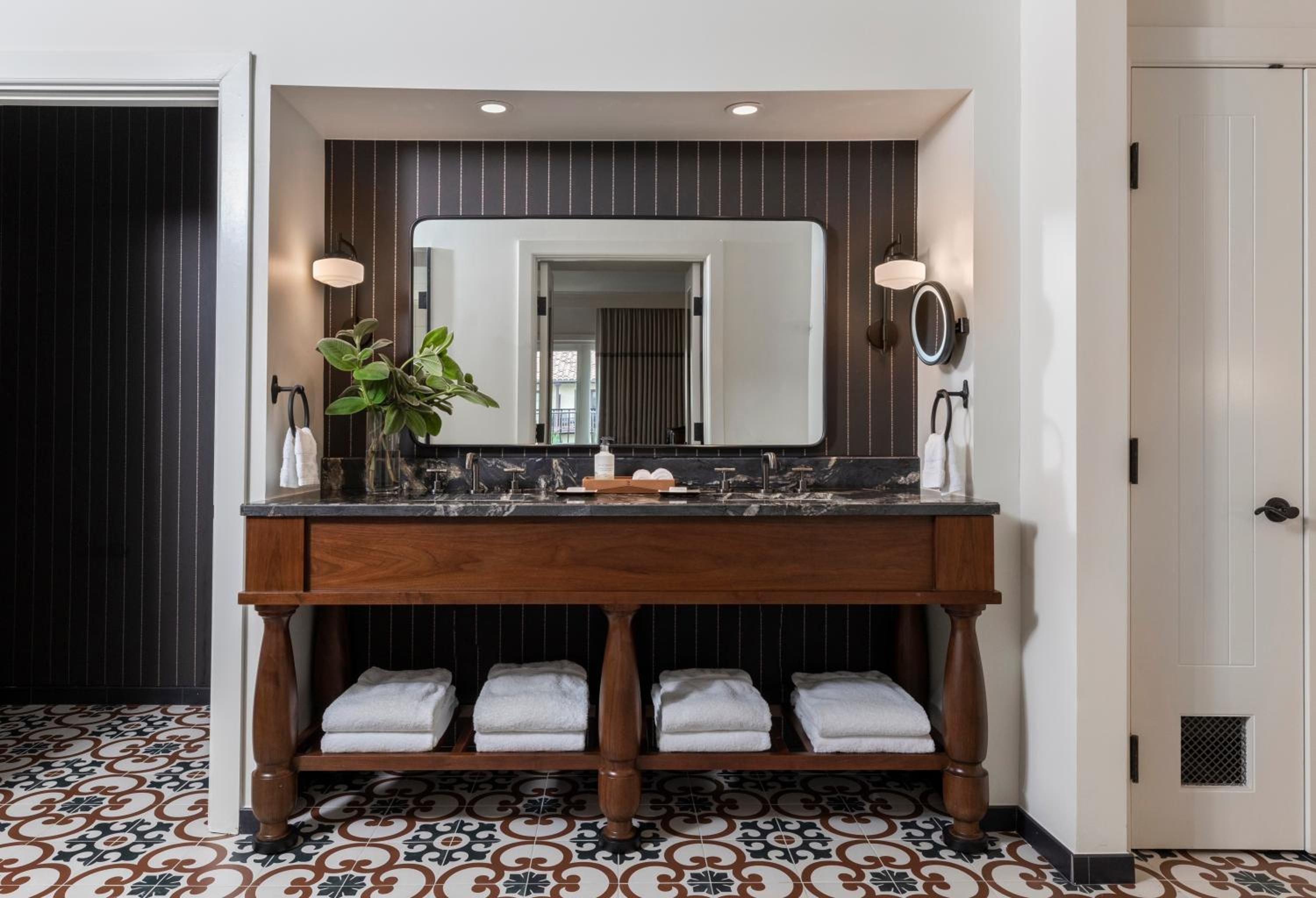 Moorish-inspired tiles meet modern luxury in this striking vanity area, where warm wood and black marble create an unexpectedly bold bathroom sanctuary.