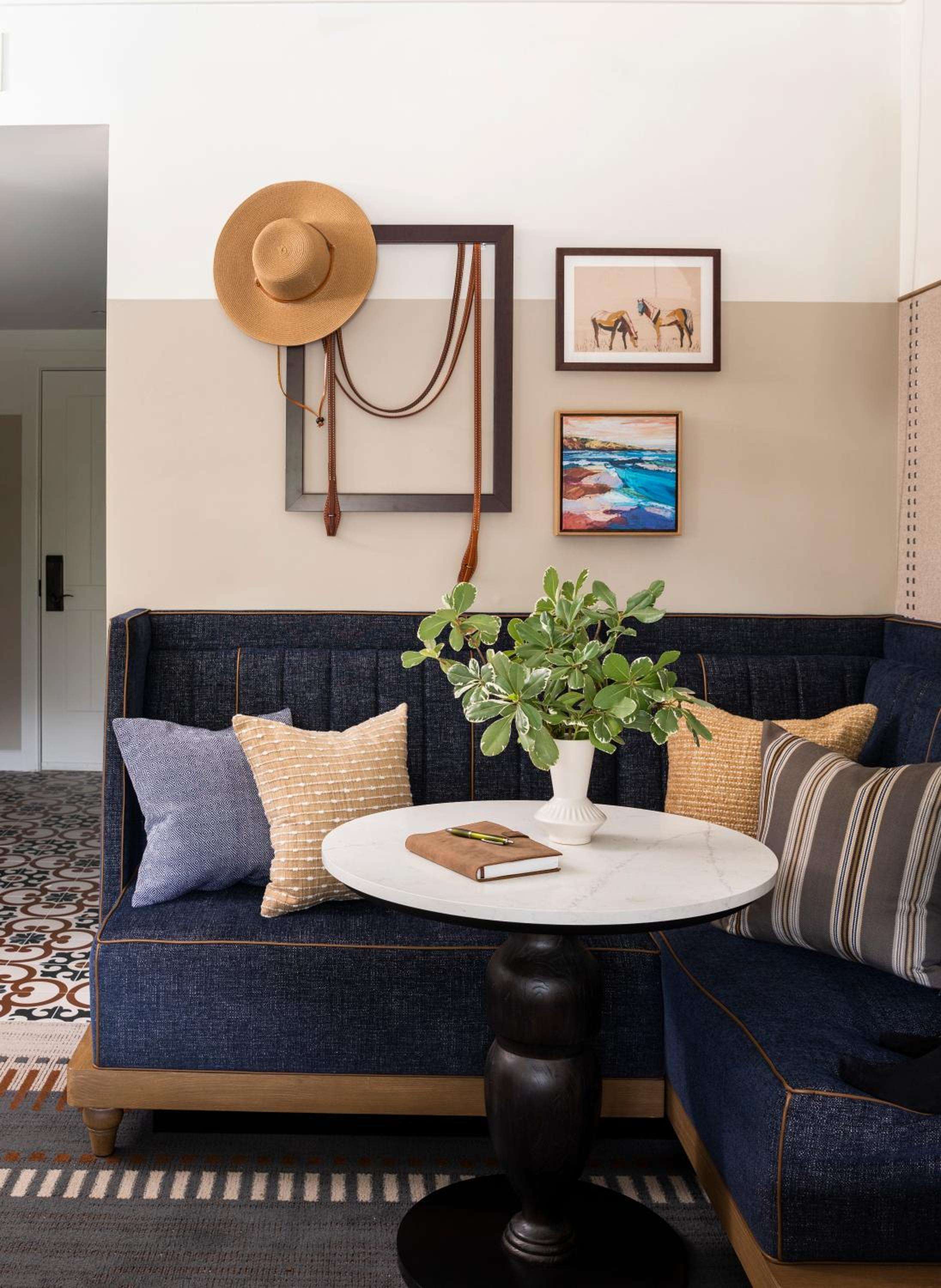 Navy banquette seating creates an intimate breakfast nook, where morning coffee pairs with handcrafted artwork and western-inspired accents that define this coastal retreat's refined ranch aesthetic.