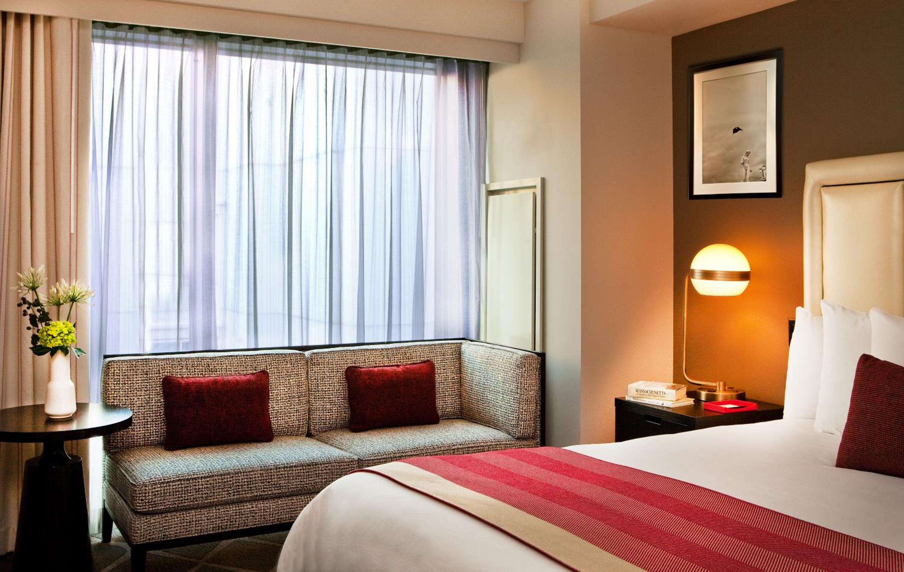 Warm amber lighting and plush burgundy accents create an inviting retreat, where textured seating meets crisp linens in this thoughtfully appointed guest room.