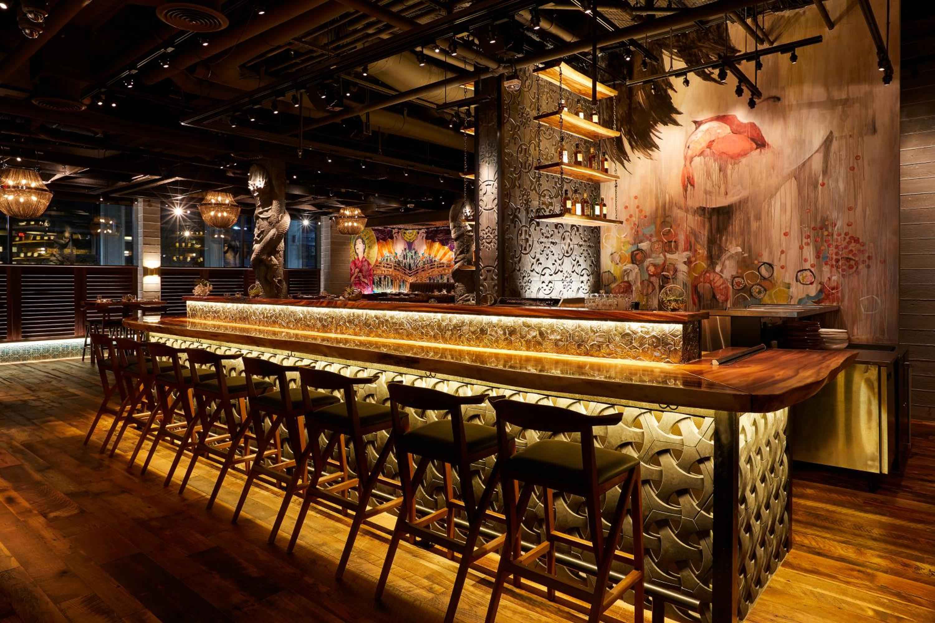 Intricate latticed panels and warm amber lighting create an intimate backdrop at this sophisticated bar, where carved details and rich wood tones invite lingering conversations.