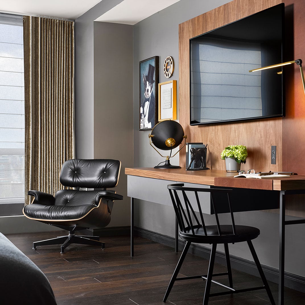Rich walnut paneling and brushed brass accents create a sophisticated workspace where mid-century design meets modern comfort in this thoughtfully appointed guest room.