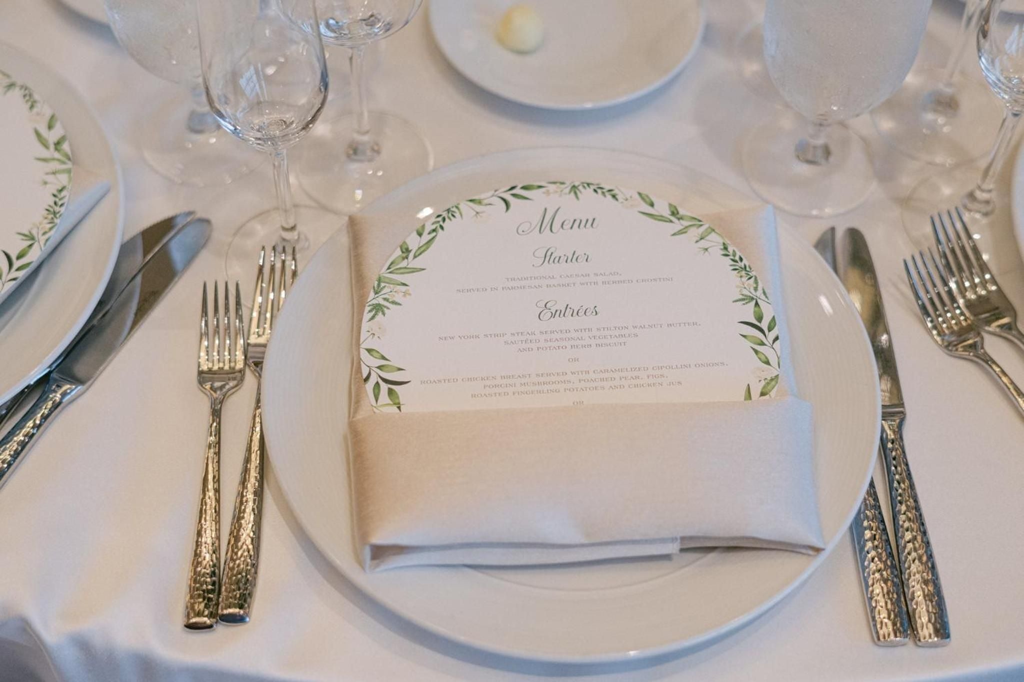 Elegant table settings with botanical-adorned menus and gleaming silverware create an intimate dining atmosphere where culinary anticipation meets refined presentation.