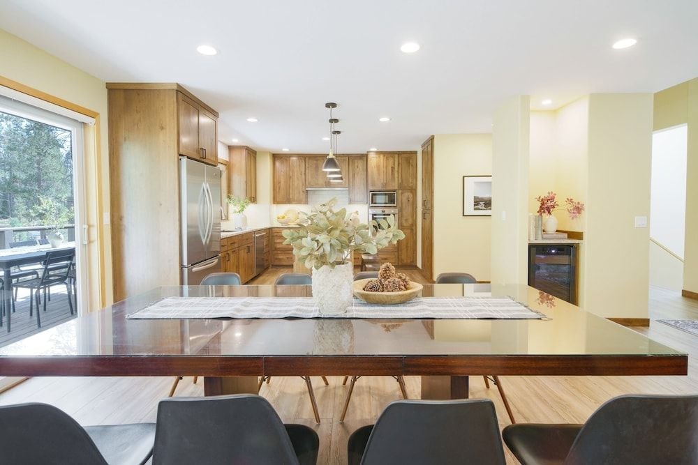 Natural light floods the open-concept space where warm wood cabinetry meets sleek pendant lighting, creating an inviting atmosphere for both cooking and conversation around the polished dining table.