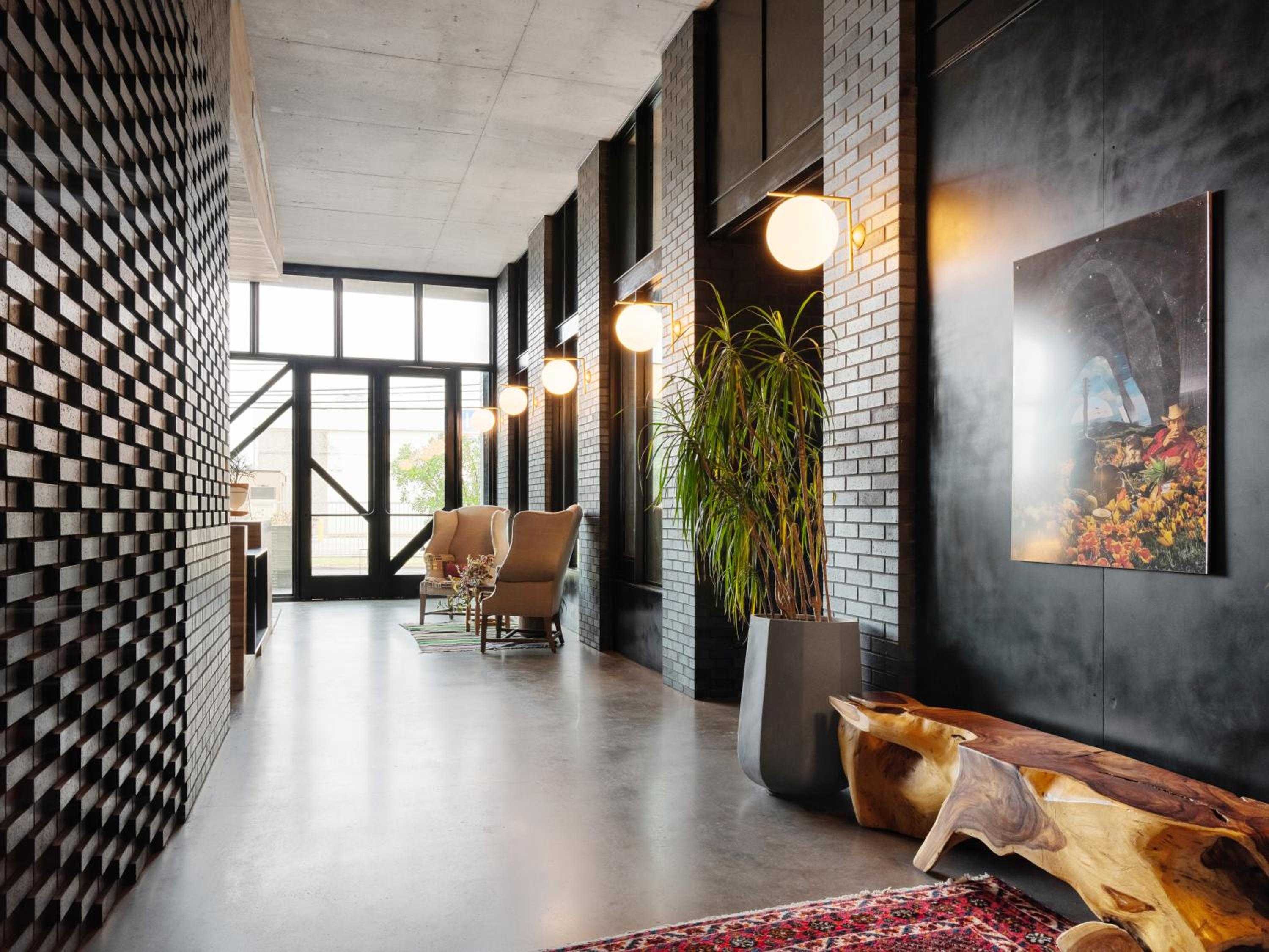 Industrial elegance meets warm hospitality in this striking corridor where geometric brick walls, pendant lighting, and natural wood benches create an unexpectedly intimate gathering space.