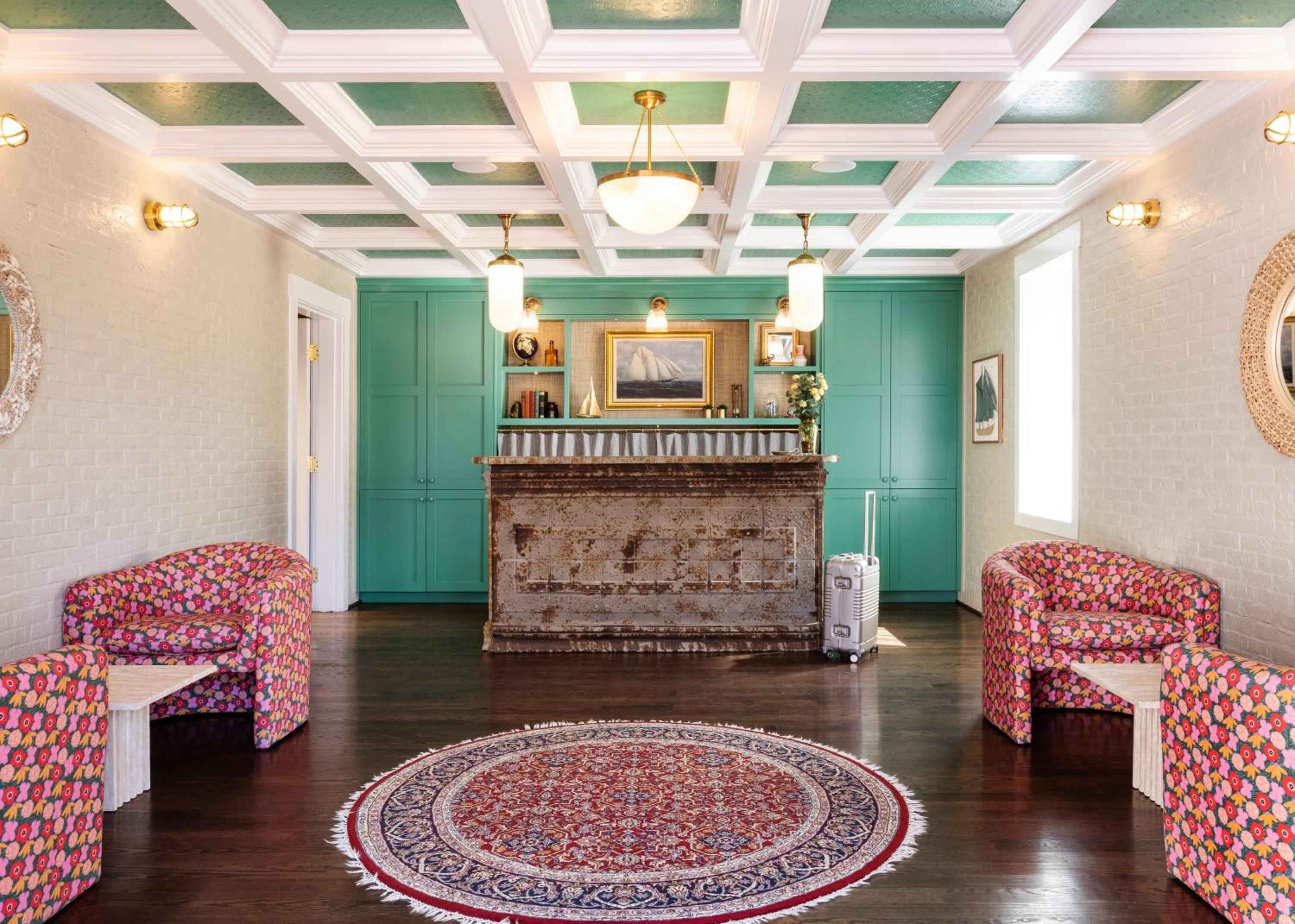 Jewel-toned chairs and weathered brick create an inviting lobby where coffered ceilings painted seafoam green hint at Wilmington's coastal charm.