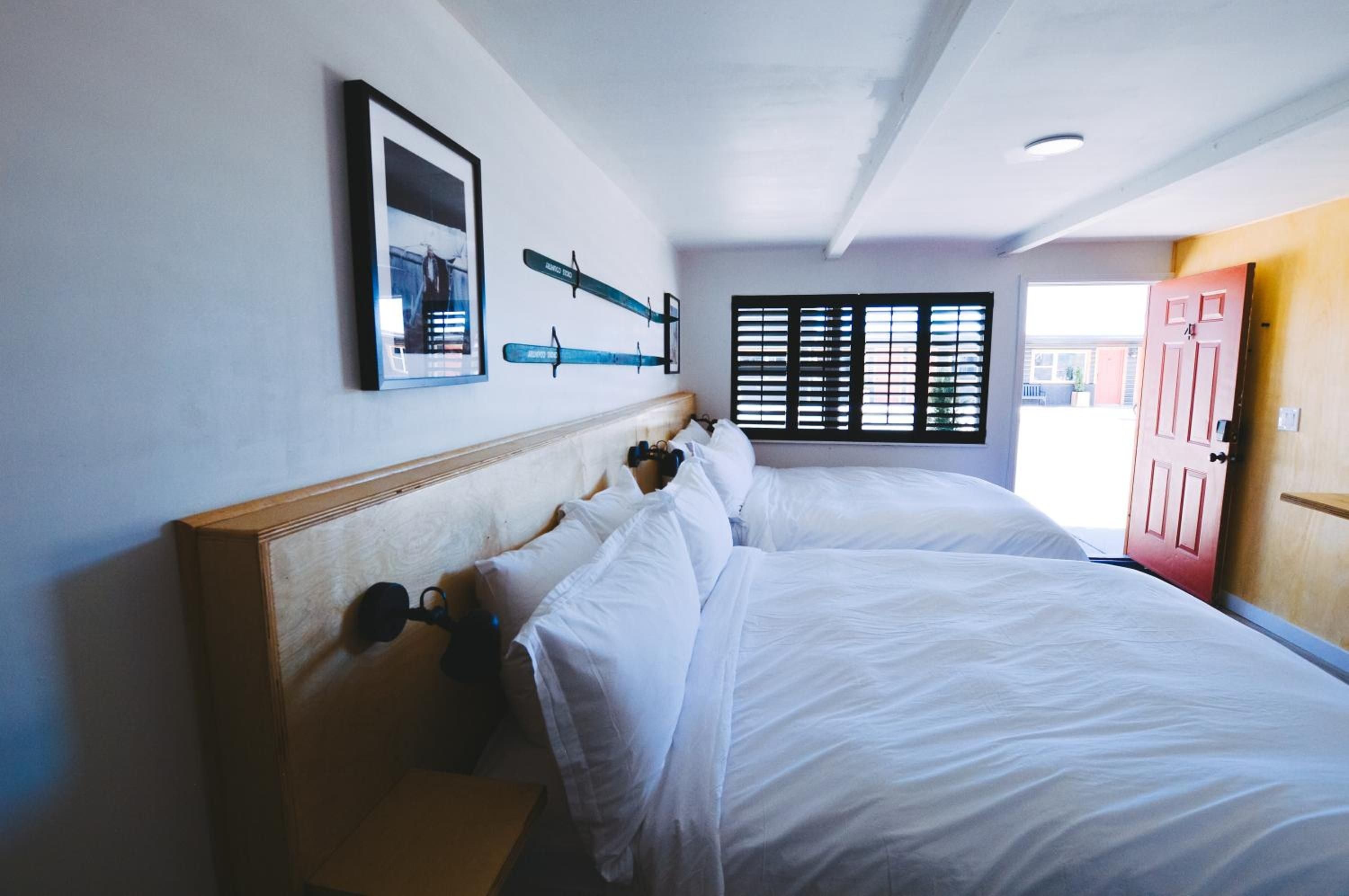 Crisp white linens and weathered wood headboards create nautical serenity in twin-bedded quarters, where paddle oars and exposed beams echo coastal mountain charm.