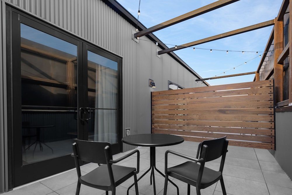 Modern corrugated steel meets warm cedar in this intimate terrace, where string lights cast evening magic over sleek outdoor dining beneath mountain sky.