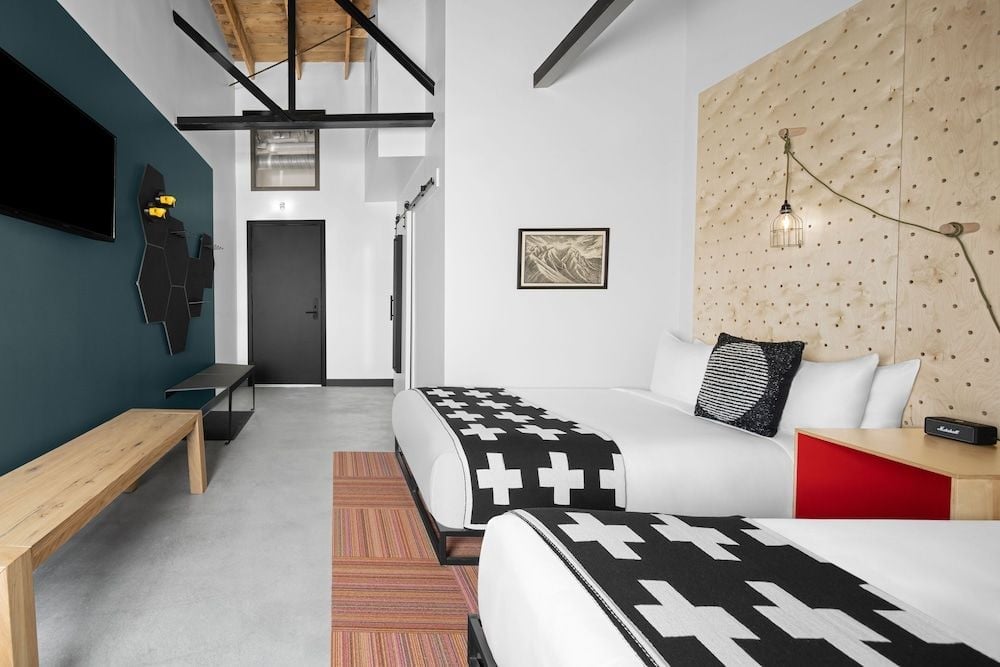 Twin beds draped in geometric crosses anchor this loft-style room, where pegboard walls and exposed beams create an industrial-meets-Scandinavian sanctuary.