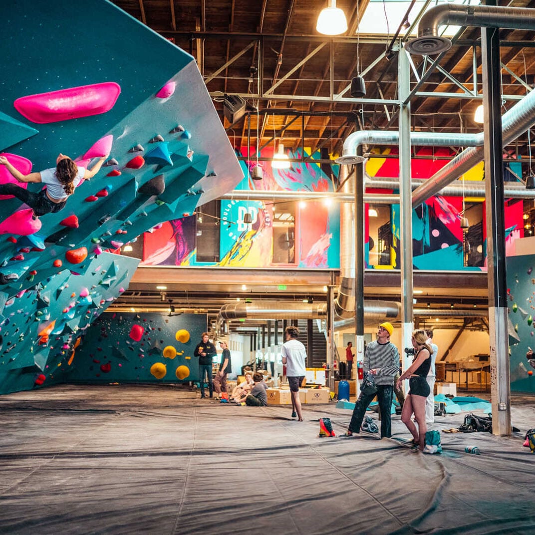 Climbers navigate colorful overhangs in this industrial-chic bouldering gym, where exposed beams and vibrant holds create an urban playground for adventurous guests.
