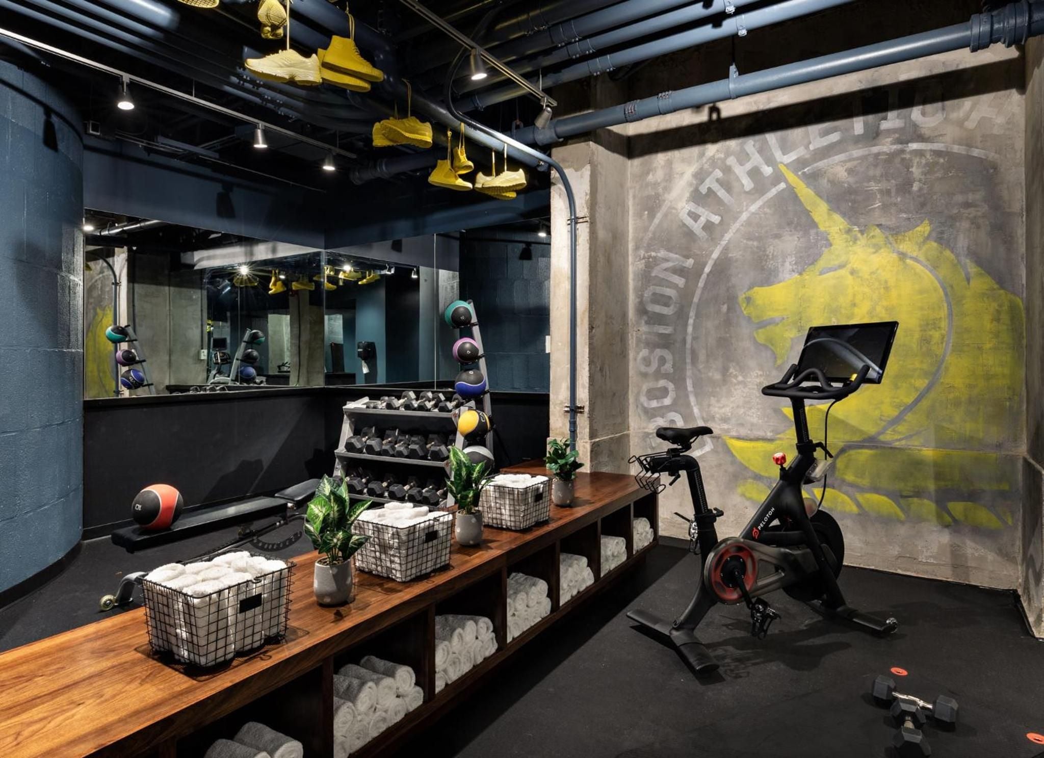 Industrial chic meets modern wellness in this basement fitness sanctuary, where exposed pipes frame sleek equipment and vibrant murals energize every workout session.