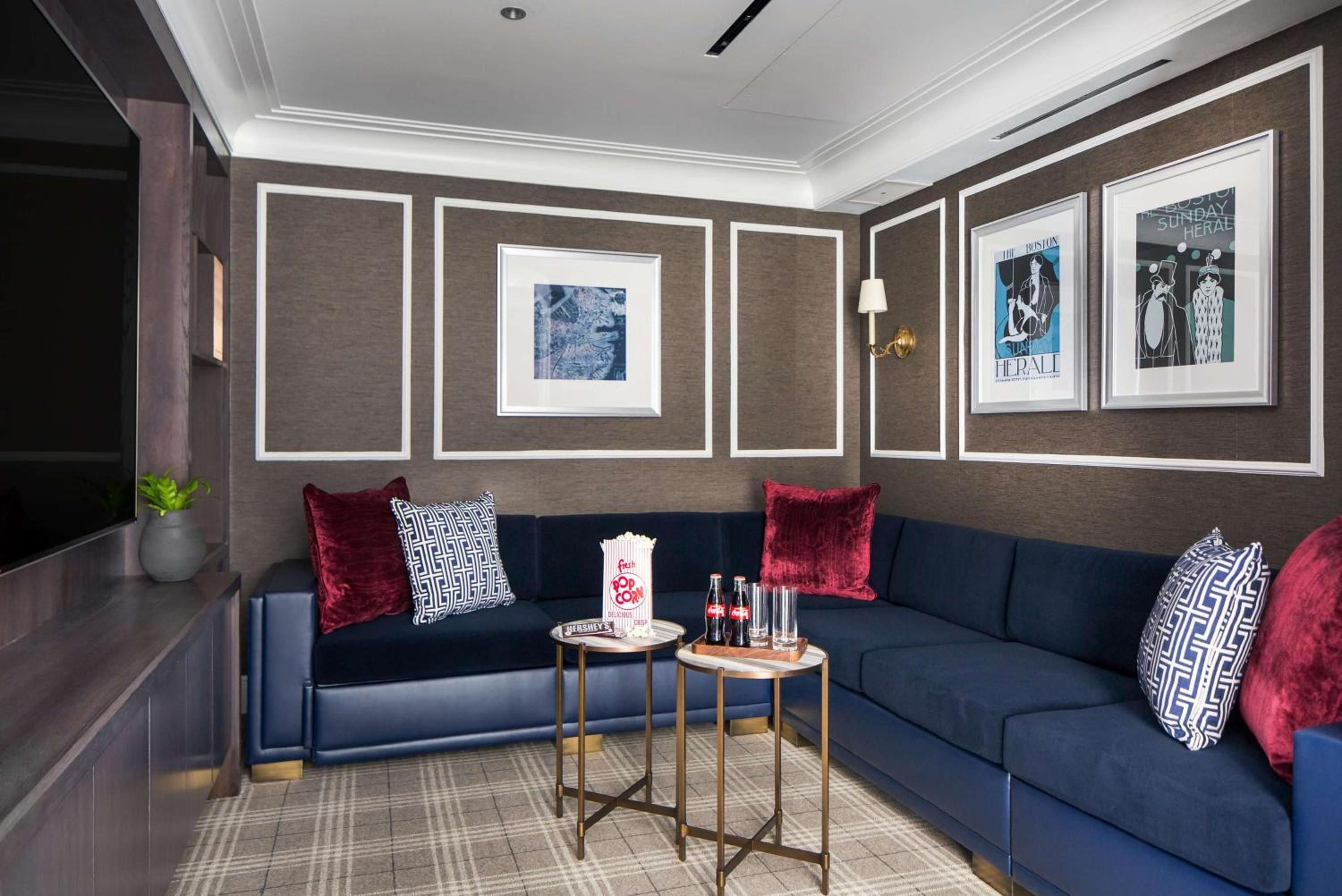 Rich navy banquettes and burgundy velvet pillows create an intimate nook, where brass-framed tables hold craft cocktails beneath thoughtfully curated artwork.