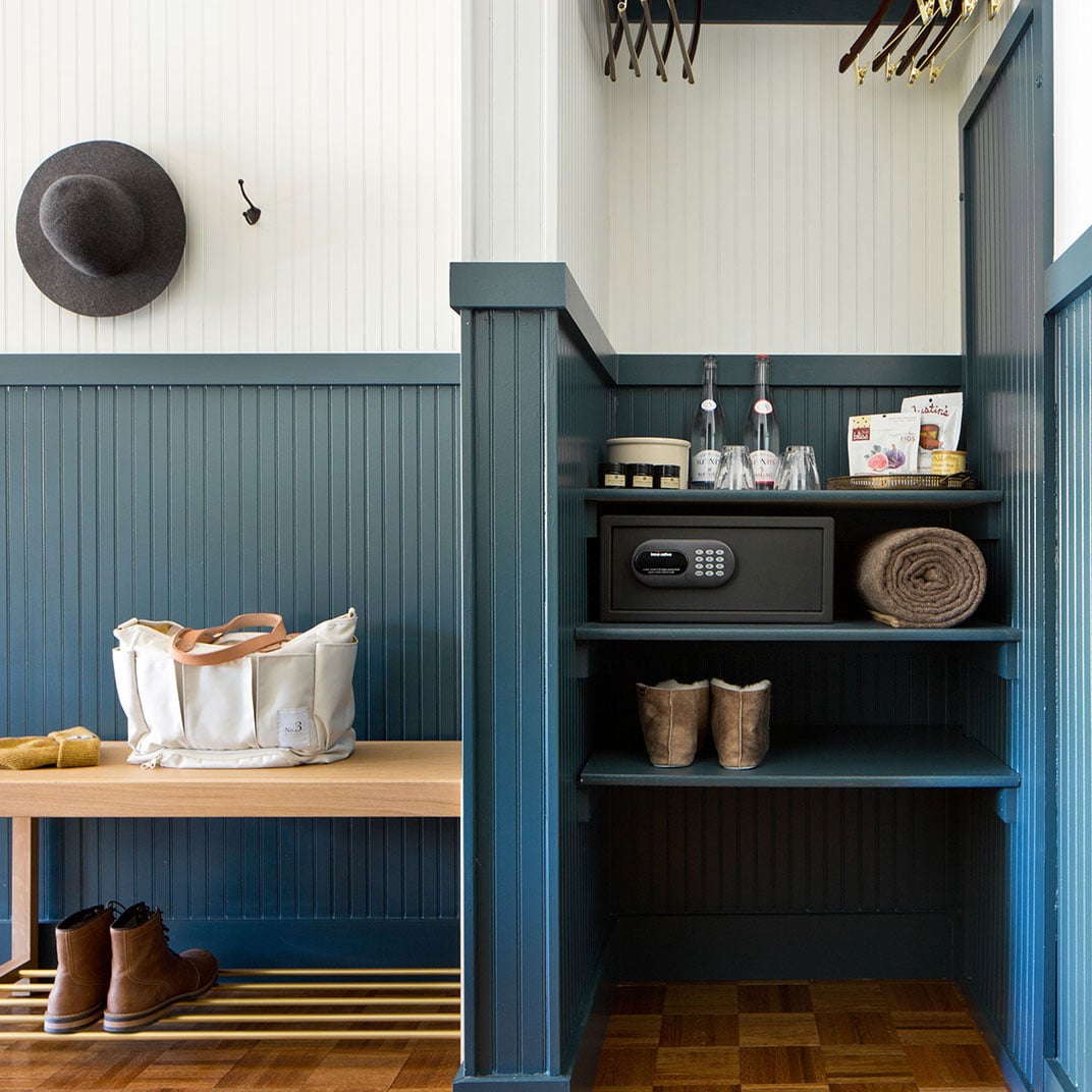 Sage-green wainscoting and rustic wood shelving create a thoughtfully appointed mudroom where leather boots and canvas totes find their perfect perch.