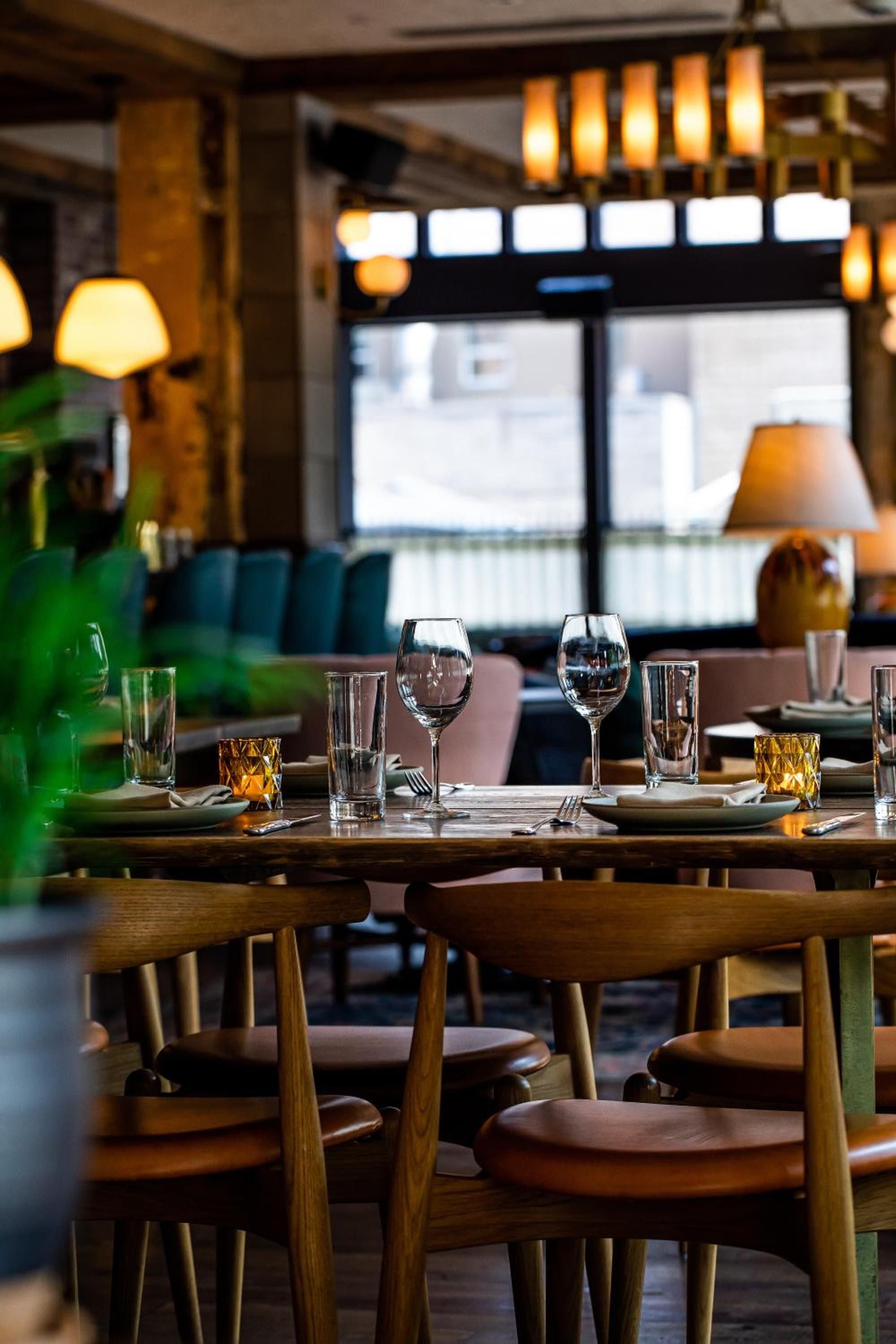 Warm amber light bathes carefully set tables where crystal glasses catch the glow, creating an intimate dining atmosphere perfect for lingering conversations.