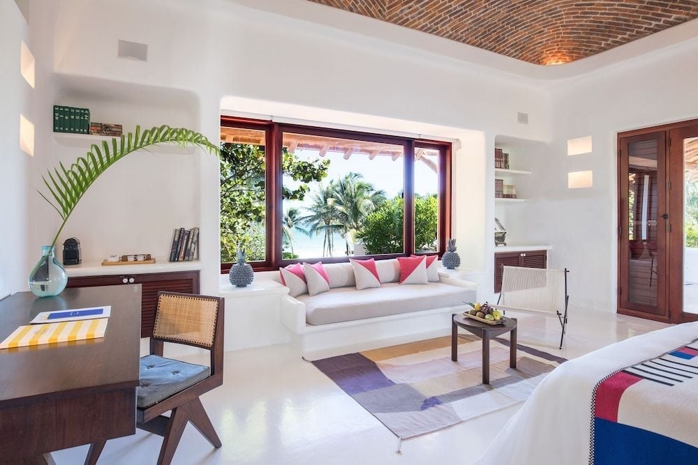 Woven palm ceilings and built-in daybeds frame jungle views in this airy suite, where natural textures meet modern comfort beneath Caribbean light.