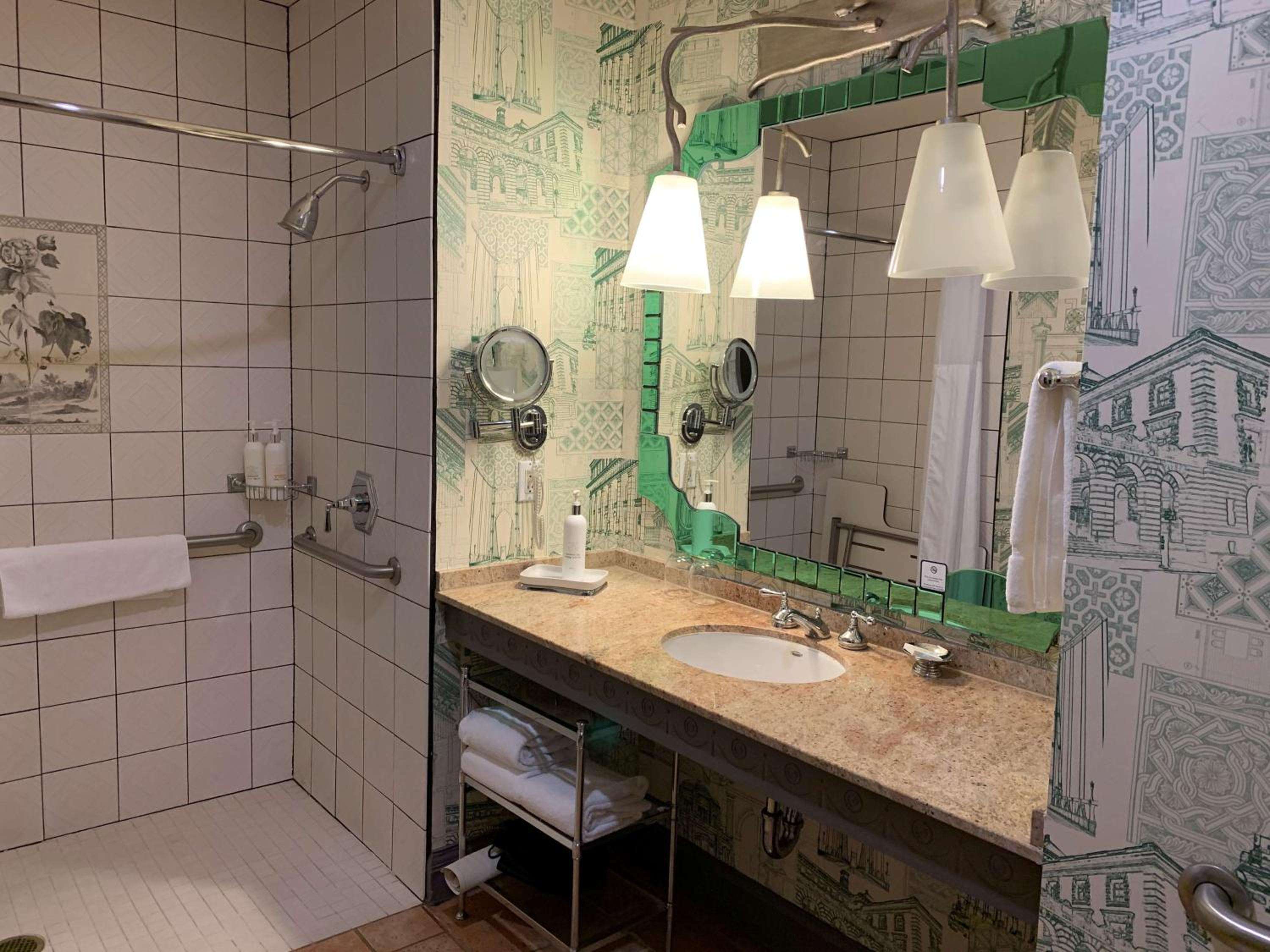 Whimsical green toile wallpaper depicting Portland landmarks transforms this marble-topped vanity into an artful tribute to the city's architectural heritage.
