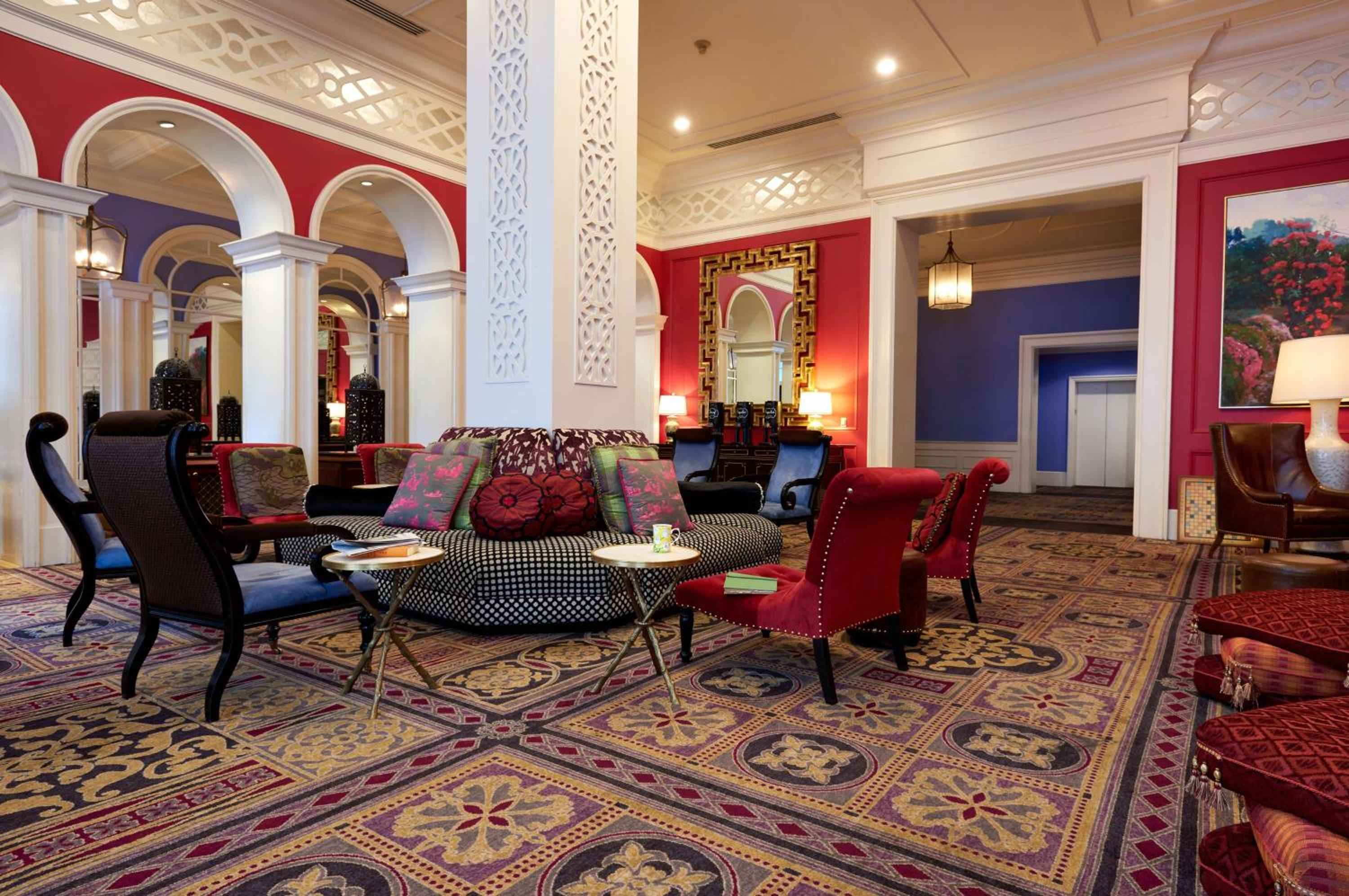 Moroccan-inspired arches and jewel-toned fabrics create an enchanting lobby where guests sink into plush seating beneath ornate coffered ceilings and glowing lanterns.