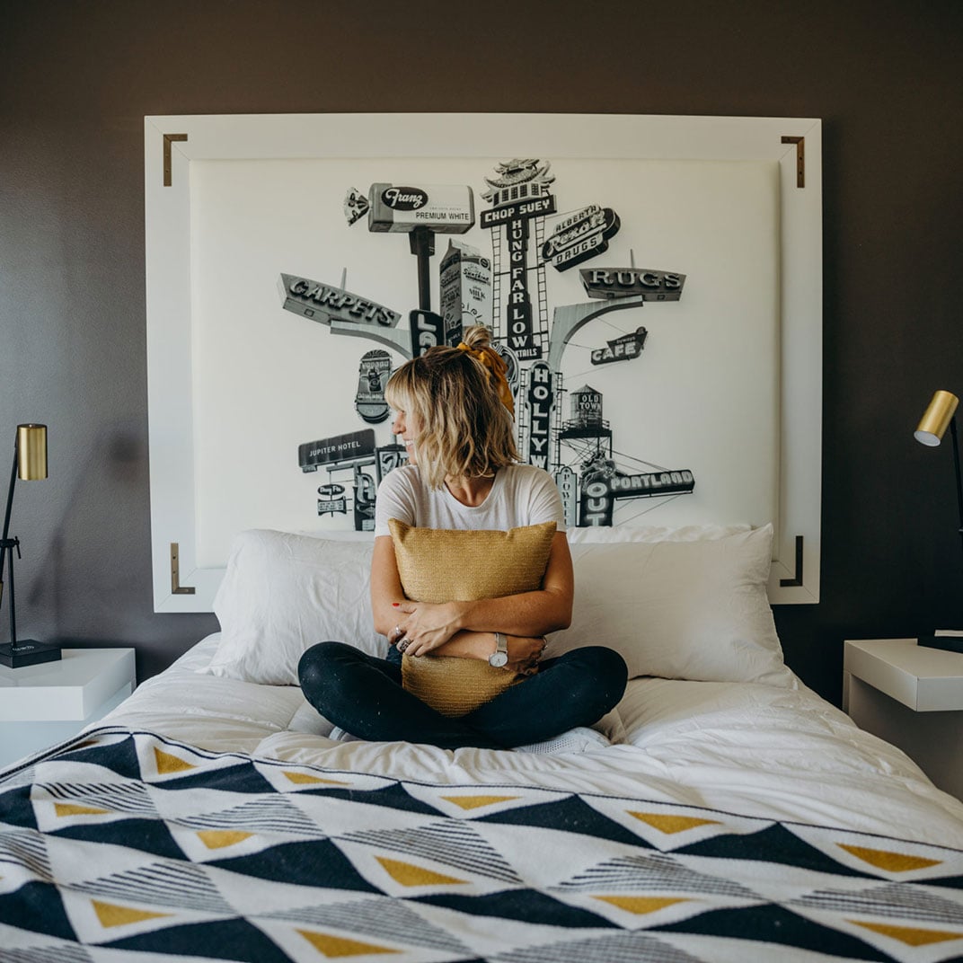 Vintage Portland signage artwork creates a playful backdrop for quiet moments, while geometric bedding and warm lighting transform the guest room into an urban sanctuary.