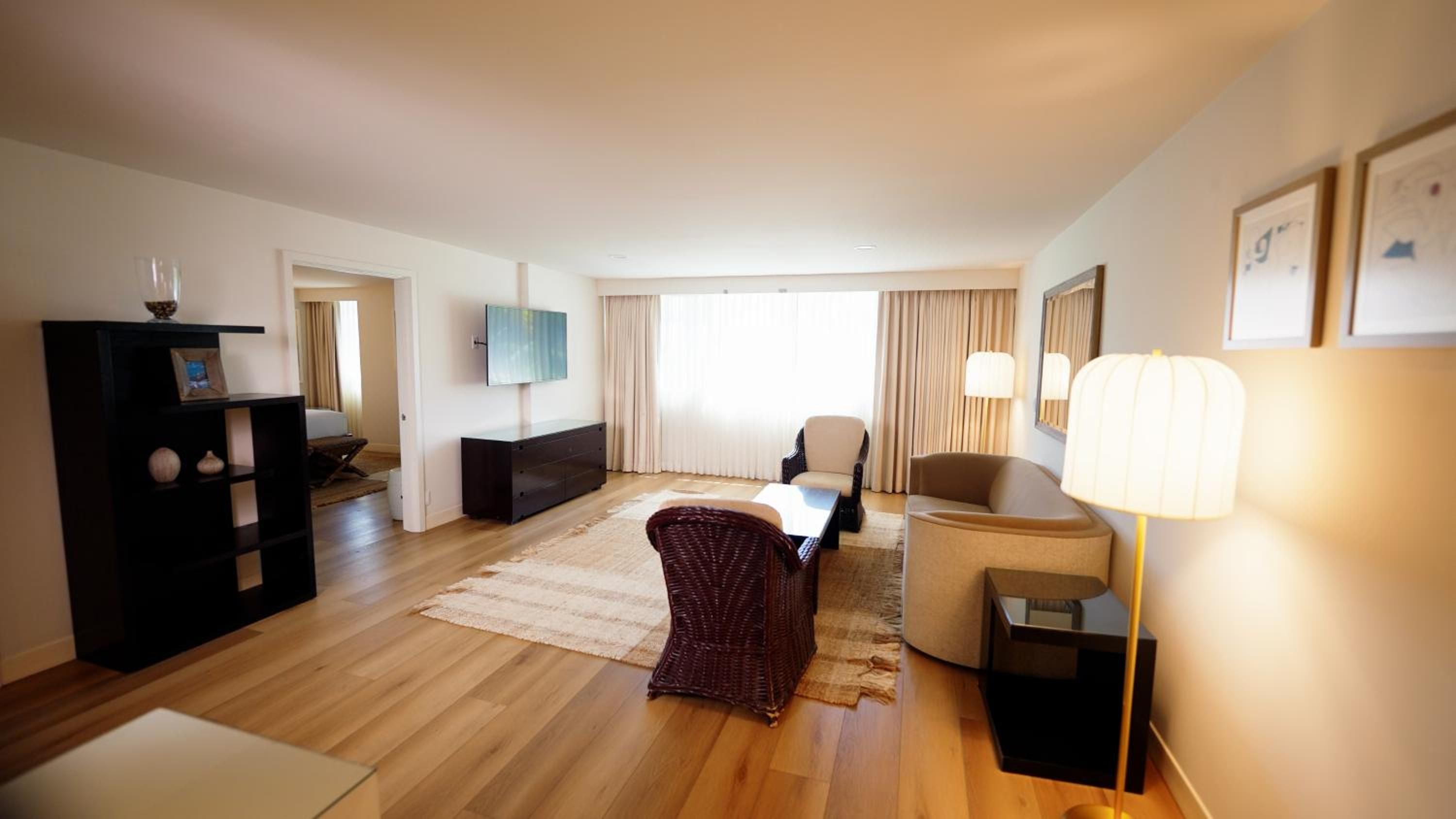 Warm wood floors and contemporary furnishings create an inviting sanctuary, where natural light filters through elegant drapes and modern artwork punctuates clean-lined sophistication.