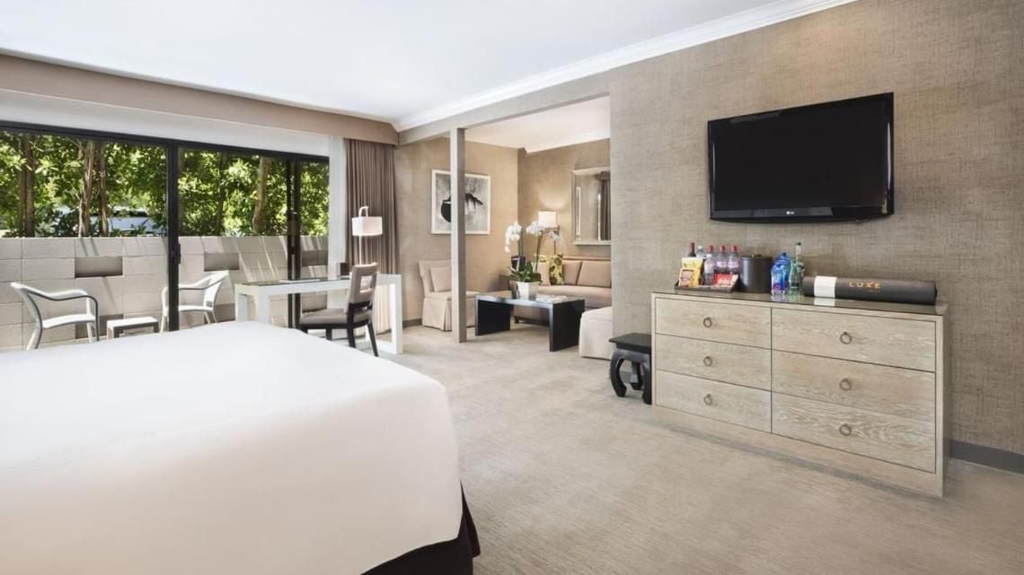 Warm textiles and contemporary furnishings create an inviting retreat, while sliding glass doors reveal a private terrace perfect for Los Angeles evening breezes.