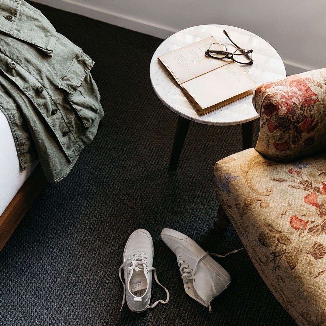 Vintage floral armchairs and marble side tables create intimate reading nooks, where afternoon light catches wire-rimmed glasses atop well-worn novels.