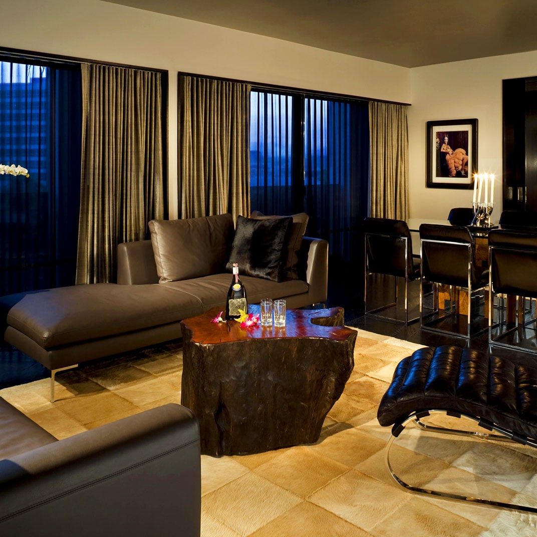Twilight transforms this sophisticated suite into an intimate retreat, where charcoal leather mingles with rich stone textures beneath the gentle glow of candlelight.