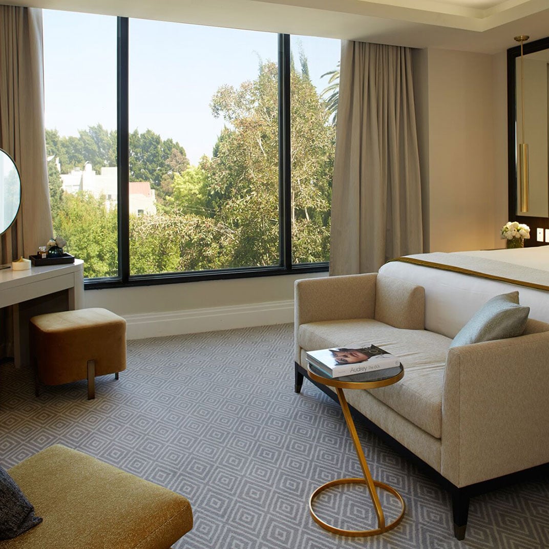 Floor-to-ceiling windows frame West Hollywood's leafy canopy while geometric carpeting and honey-toned furnishings create an intimate retreat above the bustling city below.