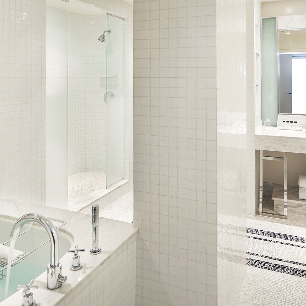 Marble surfaces and chrome fixtures create a spa-like sanctuary, where mosaic accents and glass partitions define this luxurious bathroom's sophisticated aesthetic.
