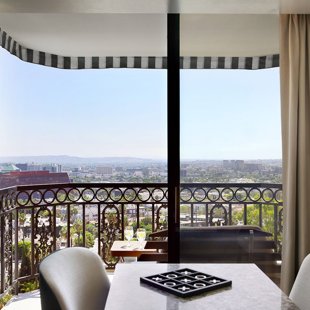 Sweeping city vistas unfold beyond ornate iron railings from this elegant suite, where afternoon light streams across marble surfaces and West Hollywood stretches endlessly below.