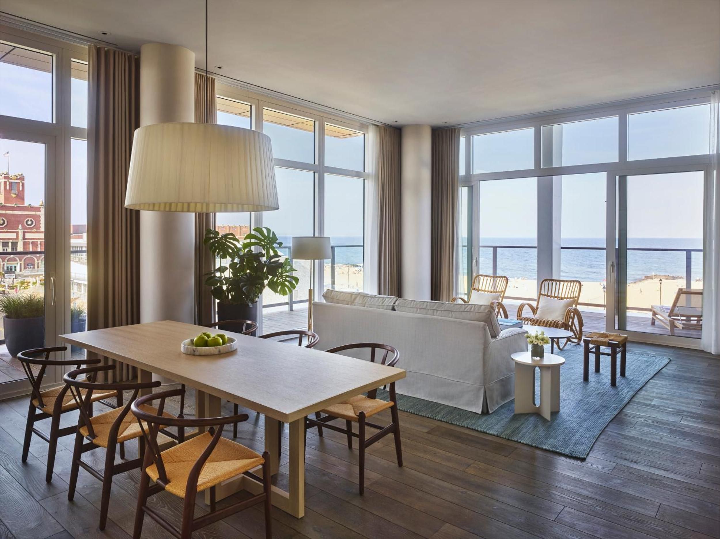 Floor-to-ceiling windows frame endless ocean views while mid-century chairs and warm wood floors create an effortlessly sophisticated retreat above Asbury Park's shoreline.