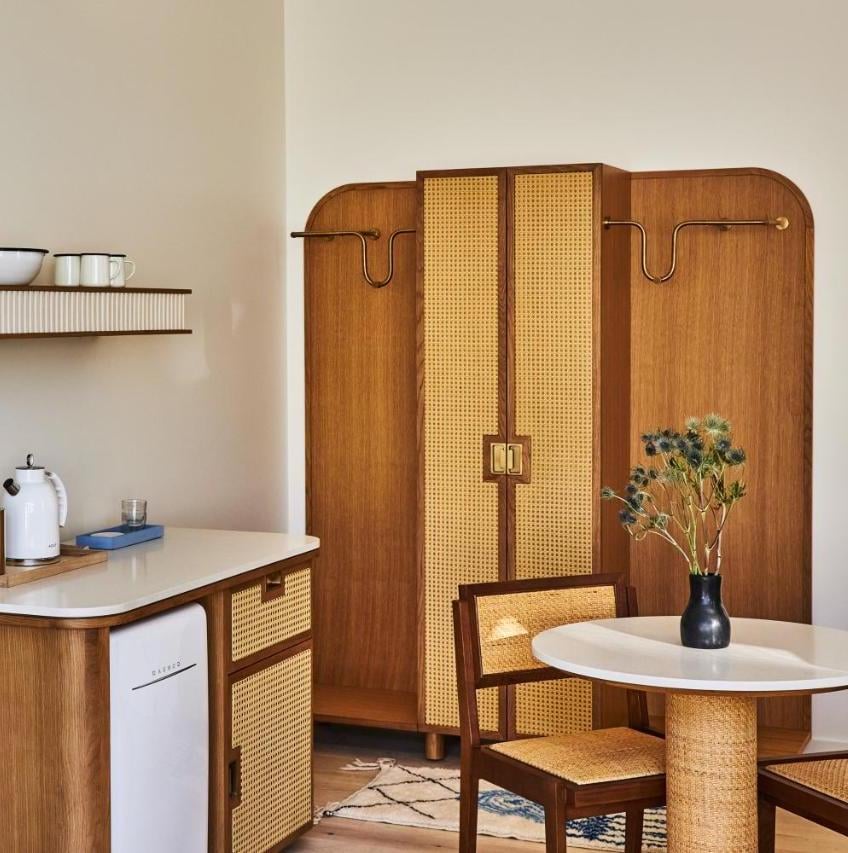 Warm walnut cabinetry and hand-woven cane details create an inviting mid-century modern aesthetic, where thoughtful design meets everyday comfort in this thoughtfully appointed space.