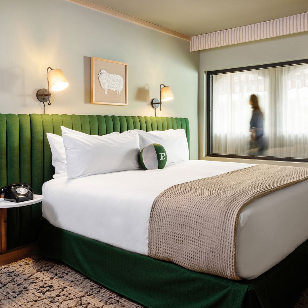 Emerald velvet headboards and vintage rotary phones create intimate sanctuaries where mid-century Hollywood glamour meets modern comfort in thoughtfully curated guest rooms.