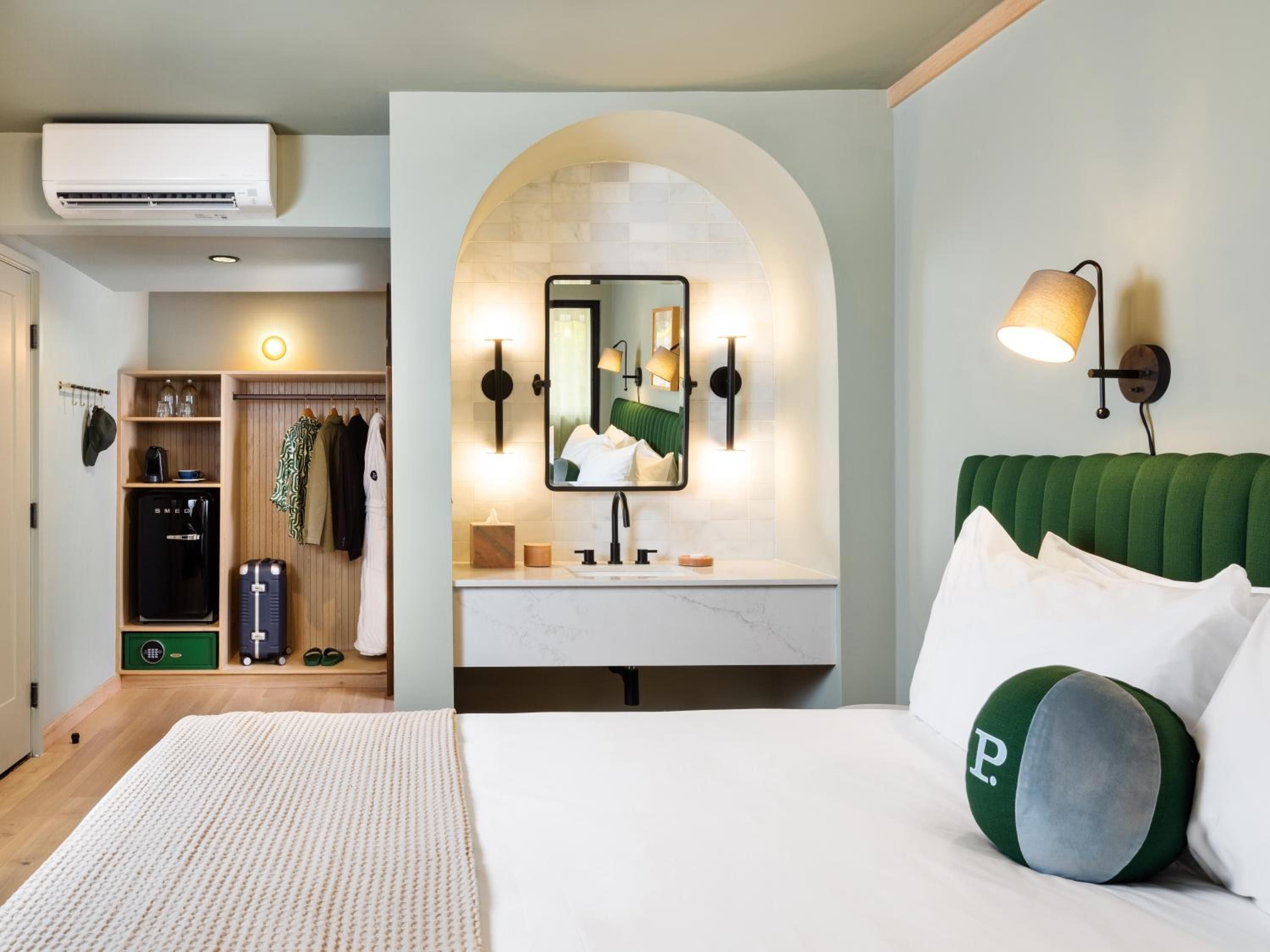 Emerald velvet headboards and warm wood accents create a sophisticated retreat, while thoughtful built-ins maximize space without sacrificing Hollywood glamour.