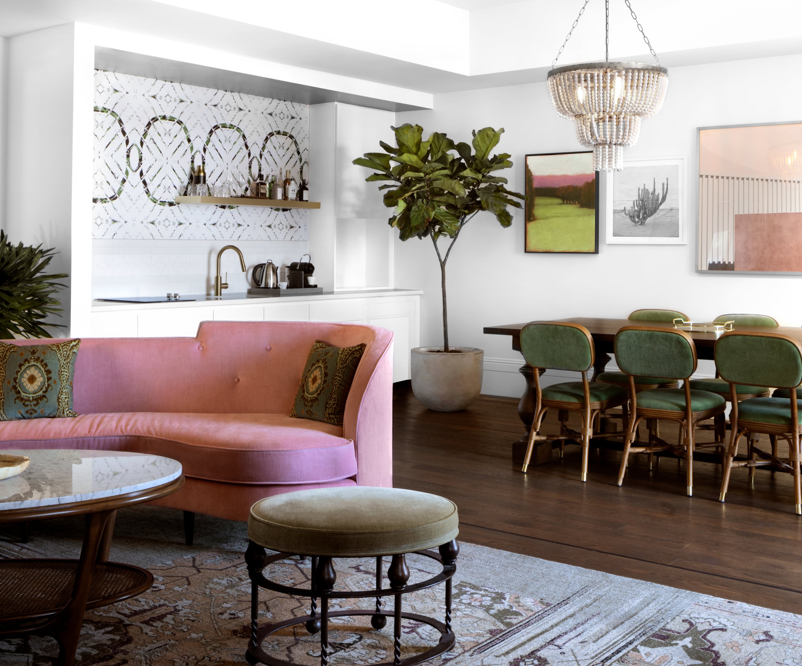 Blush velvet banquettes and sage dining chairs create an effortlessly chic living space where mid-century warmth meets contemporary sophistication beneath cascading crystal chandeliers.