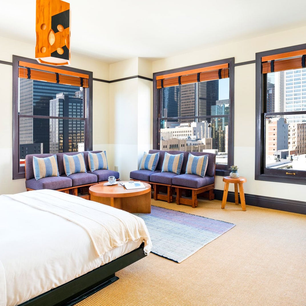 Corner windows frame downtown's skyline while purple sectional seating and warm wood create an inviting retreat high above the city streets.