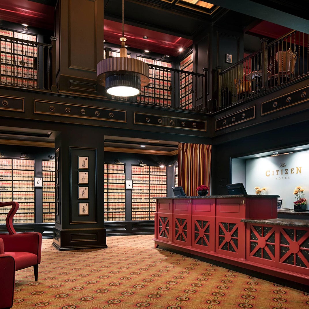 Floor-to-ceiling law books create a dramatic literary backdrop in this sophisticated lobby, where burgundy leather and rich mahogany evoke a private gentleman's club.