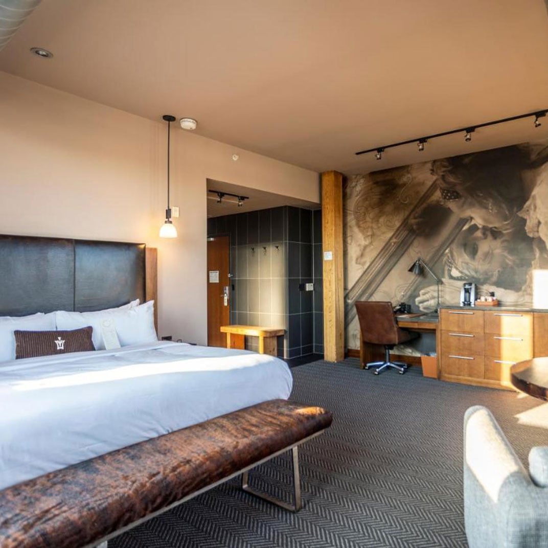 Industrial elegance meets intimate luxury in this spacious suite, where exposed brick walls and warm wood furnishings create an unexpectedly cozy urban sanctuary.