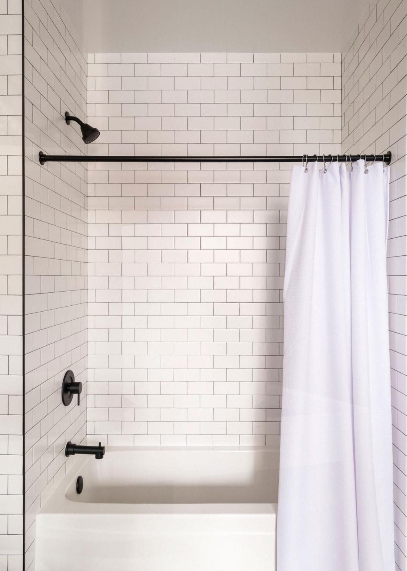 Crisp white subway tiles and matte black fixtures create a sophisticated contrast in the guest bathroom, where thoughtful details elevate everyday rituals.