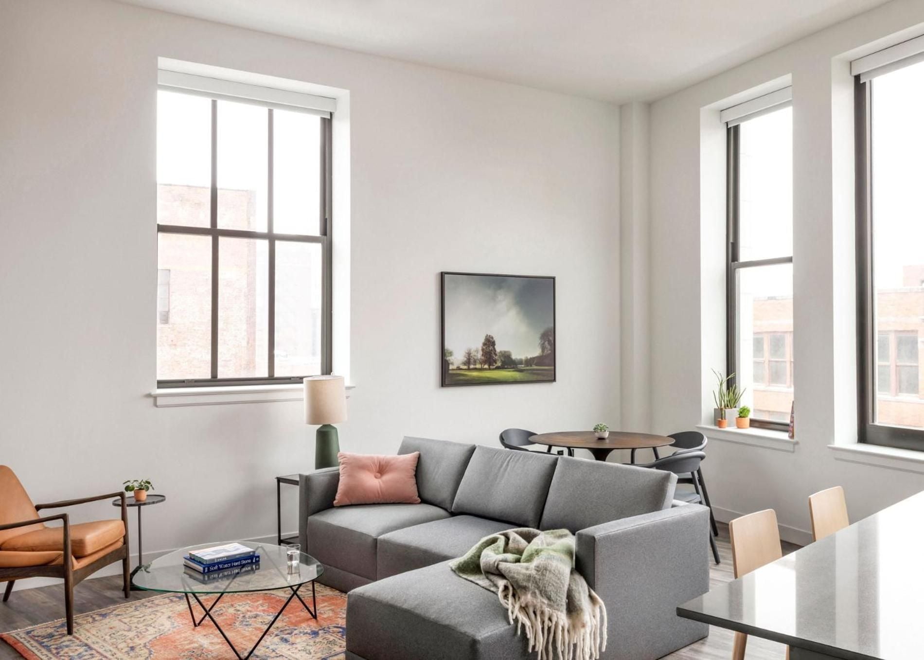 Sunlight streams through oversized windows into this thoughtfully appointed suite, where mid-century furnishings and warm textiles create an inviting retreat above Cleveland's historic streets.