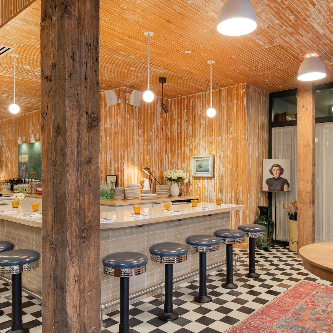 Warm bamboo walls and checkered floors create retro diner vibes at this communal counter space, where chrome stools invite lingering over locally-sourced plates.