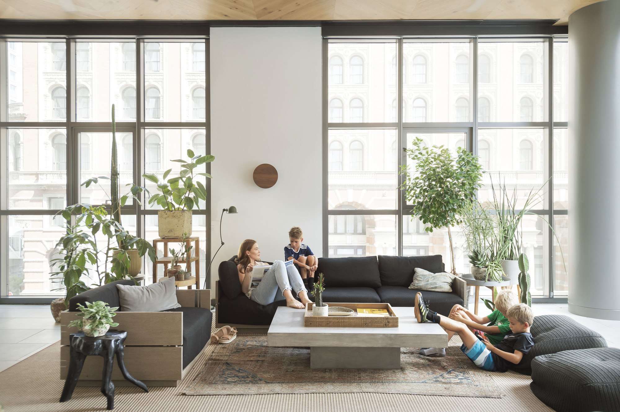 Floor-to-ceiling windows frame historic Philadelphia streetscapes while families sprawl across plush sectionals, creating an urban sanctuary where industrial charm meets residential comfort.