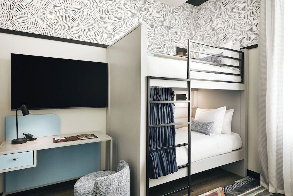 Clever bunk beds maximize space in family accommodations, where navy privacy curtains and geometric wallpaper create a playful yet sophisticated retreat for young travelers.