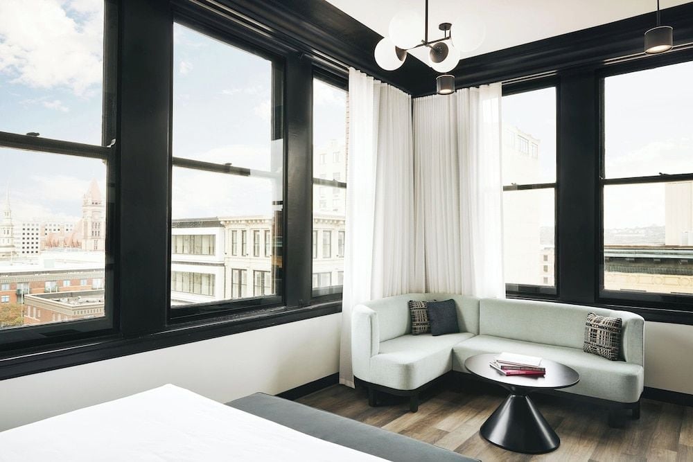 Corner windows frame Cincinnati's historic architecture while a curved banquette creates an intimate reading nook bathed in natural light and urban energy.