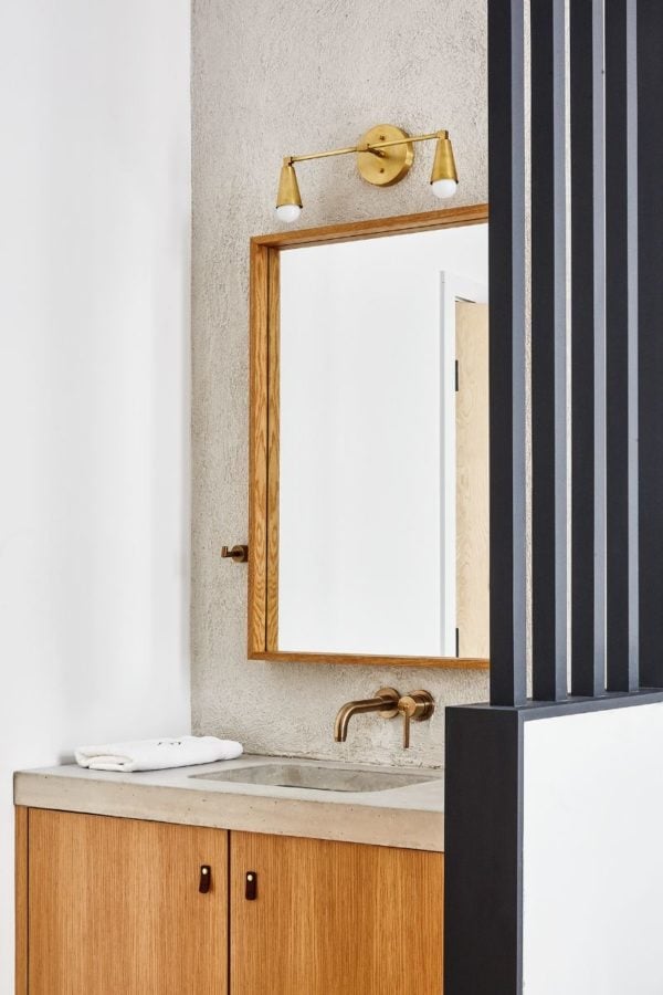 Warm brass fixtures and rich wood cabinetry create an intimate vanity corner where industrial elements meet refined craftsmanship in this thoughtfully designed guest bath.