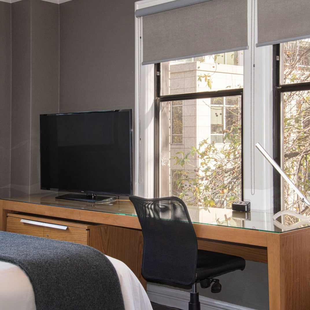 Modern workspaces blend seamlessly with relaxation in thoughtfully designed guest rooms featuring sleek wood furnishings, ergonomic seating, and oversized windows framing Seattle's urban landscape.