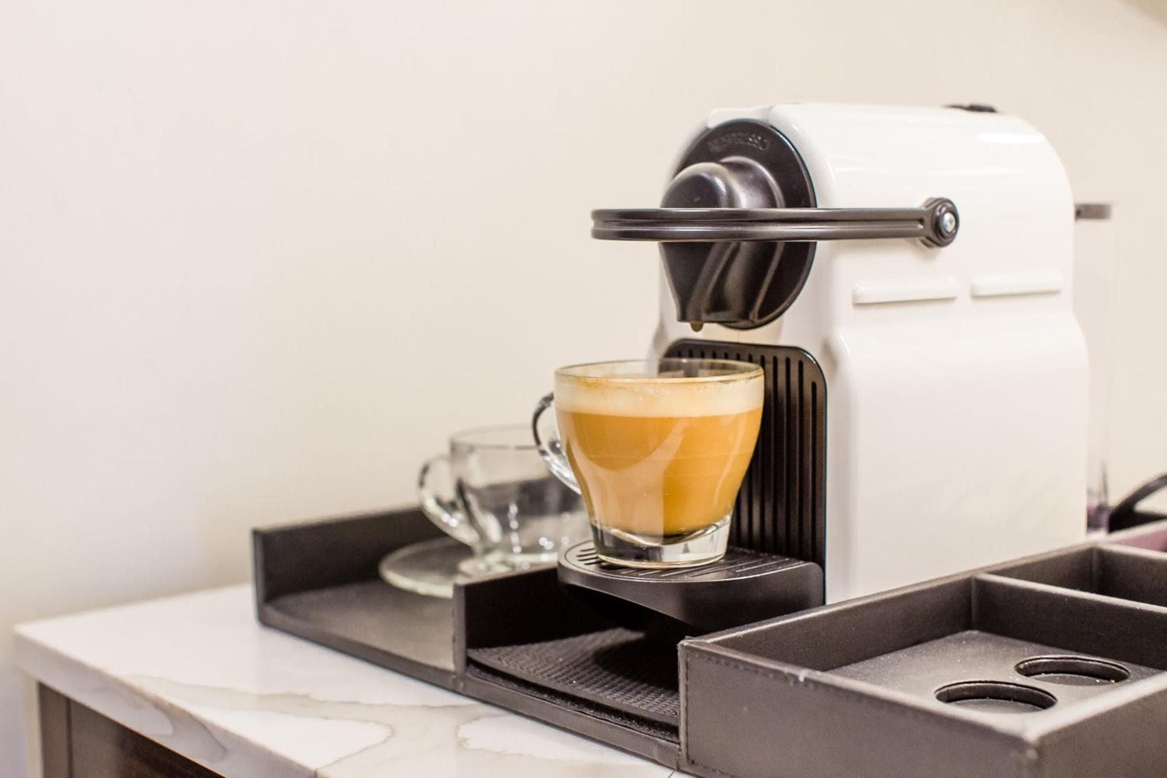 Morning ritual perfected: sleek espresso machine delivers café-quality cappuccinos to your glass cup, transforming any stay into an intimate Italian coffee bar experience.